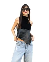 Top halter negro confeccionado en gamuza sintética en la parte superior y eco cuero en la inferior, con diseño asimétrico en el bajo y detalles de tachas metálicas plateadas en el cuello y la división de los materiales.