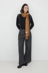 Remera de manga larga en color beige, confeccionada en tejido de punto con costuras a la vista en contraste. Presenta un corte holgado, cuello redondo y un pequeño bordado distintivo en la parte inferior.