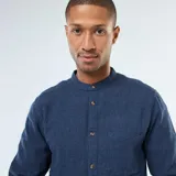 Camisa de franela azul oscuro, de manga larga, con cuello mao y cierre frontal de botones. Presenta un bolsillo de parche en el lado izquierdo del pecho.