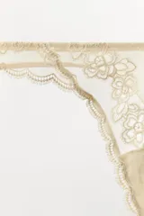 Tanga de tiro alto confeccionada en tejido mesh con detalles de encaje floral a tono y bordes festoneados.