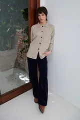 Cardigan de punto color beige, con cuello camisero, cierre frontal de botones y bolsillo aplicado en el pecho. Presenta mangas largas con puños acanalados y un corte recto y holgado.
