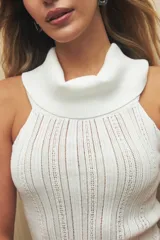 Musculosa blanca de tejido de punto calado, con cuello alto tipo polera y corte ajustado.
