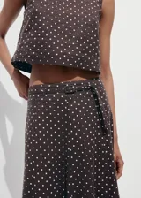 Falda midi evasé de tiro medio, confeccionada en mezcla de lino, con estampado de lunares y detalle de cinturón en la cintura.