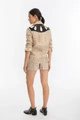 Short de lino con estampado de serpiente metalizado dorado, tiro alto, pretina estructurada, bolsillos laterales, cierre frontal y ganchito interno metálico.