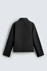 Sobrecamisa de corte relajado color beige, con cuello solapa en efecto piel de color negro. Presenta cierre frontal con cremallera, bolsillos de vivo en la cadera y mangas largas con puños ajustables.
