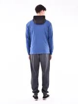 Campera deportiva con cierre frontal, capucha y diseño de bloques de color. La parte superior (hombros y capucha) es negra, y el cuerpo y mangas son de color azul vibrante, con un corte diagonal que separa ambos colores.