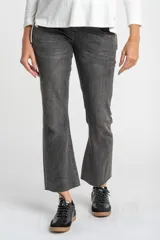 Pantalón de jeans gris oscuro, de corte flare y tiro medio, con ruedo desflecado.
