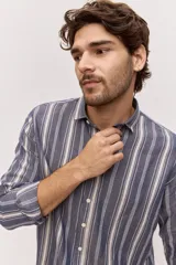 Camisa de manga larga de lino con diseño a rayas en tonos celestes y blancos, cuello camisero clásico y cierre frontal de botones.
