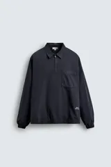 Camisa relaxed fit color azul marino, confeccionada en tejido de algodón con efecto lavado. Presenta cuello solapa, cierre frontal de cremallera, manga larga con puños elásticos y bolsillo de parche en el pecho. Incluye un pequeño estampado blanco en la parte inferior derecha.