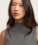 Blusa sin mangas de cuello alto, confeccionada en tejido rib acanalado de color gris. Presenta un diseño ajustado al cuerpo y estilo minimalista.