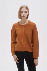 Sweater de tejido de punto color verde oliva, con cuello redondo y manga larga. Presenta un diseño de punto trenzado en el frente y mangas, contrastando con un tejido acanalado liso en el lado derecho del torso.