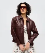 Campera bomber de poliuretano color bordó, con cuello inglés, cierre frontal, mangas largas con puños abotonados y bolsillos delanteros con solapa.