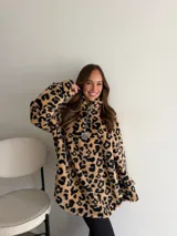 Buzo de peluche con estampado animal print de leopardo, cuello alto con cierre frontal parcial y tirador metálico decorativo.
