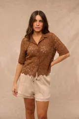 Camisa de encaje color marrón chocolate, con cuello solapa, mangas cortas y cierre frontal con botones.
