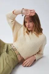 Sweater color crema de tejido de punto acanalado, corte cropped, cuello redondo y mangas largas.