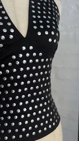 Top negro con escote halter y estampado de lunares plateados.