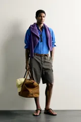 Camisa de corte relajado confeccionada en tejido de algodón de color azul, con cuello abotonado, manga larga, bolsillo frontal de parche y cierre de botones.