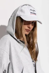 Gorro blanco de algodón con visera, con bordado frontal de la frase "Health is Wealth" en azul y rojo.