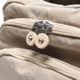 Mochila urbana de tela arrugada color beige, con múltiples compartimentos con cierre, bolsillos laterales y logo circular de la marca en el frente.