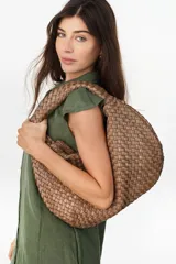 Bolso tipo hobo de cuero marrón oscuro, con diseño trenzado y asa integrada al hombro.