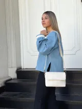 Camisa celeste de jean con cuello en V, mangas largas abullonadas con puños de encaje y cierre frontal con botones.