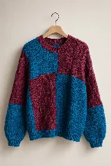 Sweater de lana merino con diseño colorblock en tonos bordó y azul turquesa, de corte relajado, con cuello redondo y texturas combinadas en punto arroz y ochos.