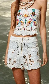Short blanco de tela calada con diseño de palmeras y frutos, con broche de gancho y cierre. Terminación en puntilla y calce holgado en las piernas.