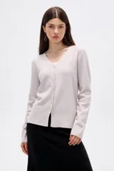 Cardigan de punto color natural, al cuerpo, con escote en V profundo y cierre frontal de botones.