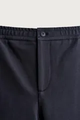 Pantalón negro confeccionado en mezcla de algodón, con cintura elástica, bolsillos frontales y cierre con cremallera y botón.