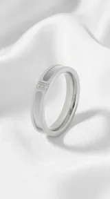 Anillo de acero con banda central de nácar y detalle de circonias incrustadas.