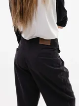 Pantalón de vestir color negro, de corte holgado y cintura de altura media. Presenta pinzas frontales, bolsillos con solapa decorativa y bolsillos traseros tipo ojal.