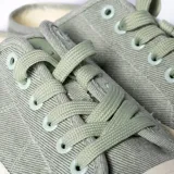 Zapatilla urbana color verde con cordones y suela blanca.
