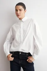 Camisa de corte oversized, color blanco, con cuello clásico, cierre frontal de botones y mangas largas.