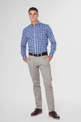 Pantalón de gabardina color marrón claro, corte slim fit, con bolsillos laterales y traseros. Se ajusta a la cintura con cinturón de cuero marrón.