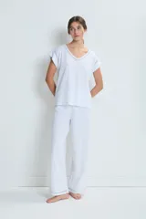 Pijama de dos piezas en color blanco, confeccionado en algodón. Incluye una remera de manga corta con cuello en V y detalles de calados, y un pantalón de corte recto con detalles de calados en el ruedo.