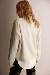 Buzo oversized color beige con interior cepillado suave. Presenta hombros caídos y un diseño de texto en el pecho que dice "HAMPSTEAD HEATH London, 1998" en rojo y negro. Tiene ribete acanalado en cuello, puños y bajo.