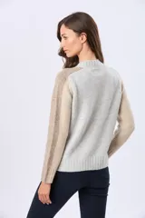 Buzo tejido de abrigo en color gris con mangas en combinación de tonos beige y tostado. Presenta cuello redondo y detalles de textura acanalada en puños y cuello.