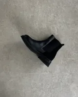 Botines Chelsea de cuero marrón con elástico negro en los laterales y suela de goma negra.