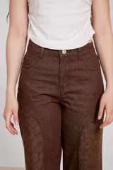 Pantalon de jean azul de corte ancho, con paneles laterales estampados con diseño floral sutil y costuras visibles.