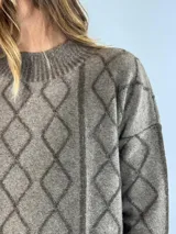 Sweater de lana color bordó con cuello alto y diseño de rombos y líneas verticales en rojo. Tiene puños y dobladillo acanalados.