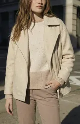 Campera de abrigo color crema, con cuello solapa y cierre asimétrico frontal. Presenta textura bouclé o de lana rizada.