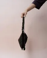 Bolso de hombro tipo hobo confeccionado en gamuza suave color marrón oscuro. Presenta un diseño de media luna con bordes trenzados, cierre superior con tiradores de cuero anudado y una correa ajustable y desmontable con herrajes metálicos.