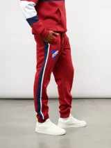Pantalon de jogging azul de felpa, con franjas laterales en blanco y azul marino. Presenta el escudo del Club Nacional de Football en el muslo derecho y el logo de Umbro en el izquierdo.