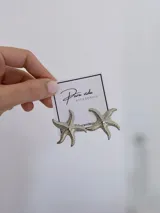 Aros con diseño de estrella de mar en color plateado, con textura rugosa y acabado brillante.
