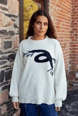 Sweater de punto color blanco con diseño de raíces en color azul marino en el frente, de corte holgado, cuello redondo y mangas largas con puños ajustados.