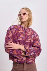 Campera bomber corta color bordó con estampado abstracto en tonos naranja y lila, cierre frontal y mangas largas abullonadas.