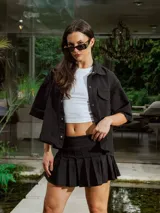 Pollera corta negra de gabardina, estilo plisado, con tiro medio y bordado frontal.