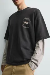 Sudadera de manga corta con corte relajado, confeccionada en algodón con interior de rizo. Presenta cuello redondo con detalle de costura en V, efecto lavado y estampado gráfico en el frente.