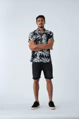 Camisa de manga corta con estampado botánico de hojas en tonos azul y blanco. Presenta cuello clásico, cierre frontal abotonado y corte slim.