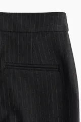 Pantalón de vestir con corte bootcut, confeccionado en tela negra con diseño de rayas finas verticales. Presenta cierre frontal con pretina prolongada, bolsillos laterales al bies y bolsillos traseros ribeteados, con detalle de raya marcada en el frente y la espalda.